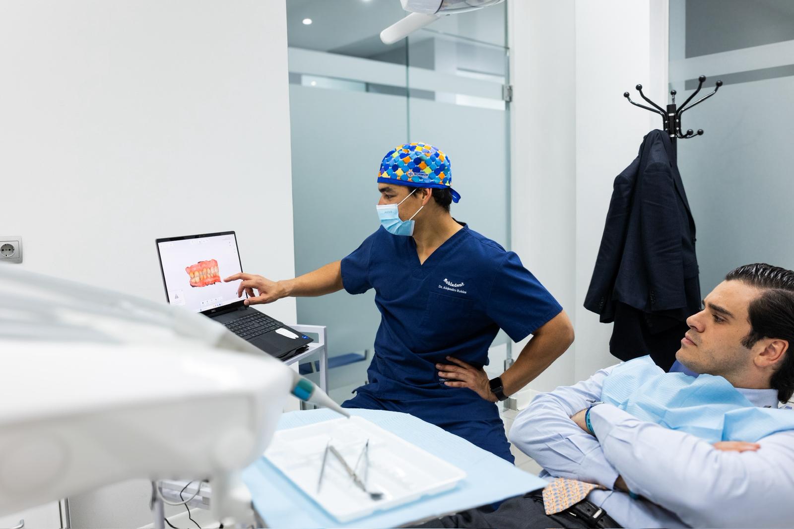 dentista explicando procedimiento dental a paciente en consulta con pantalla