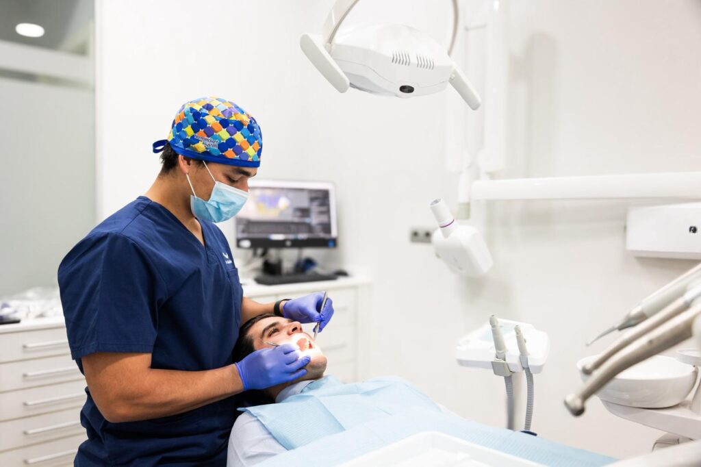 dentista realizando tratamiento dental a paciente en consulta con luz clinica